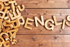 The image shows wooden letters spelling \"English.\" The letters are scattered and appear to be in the process of being assembled.